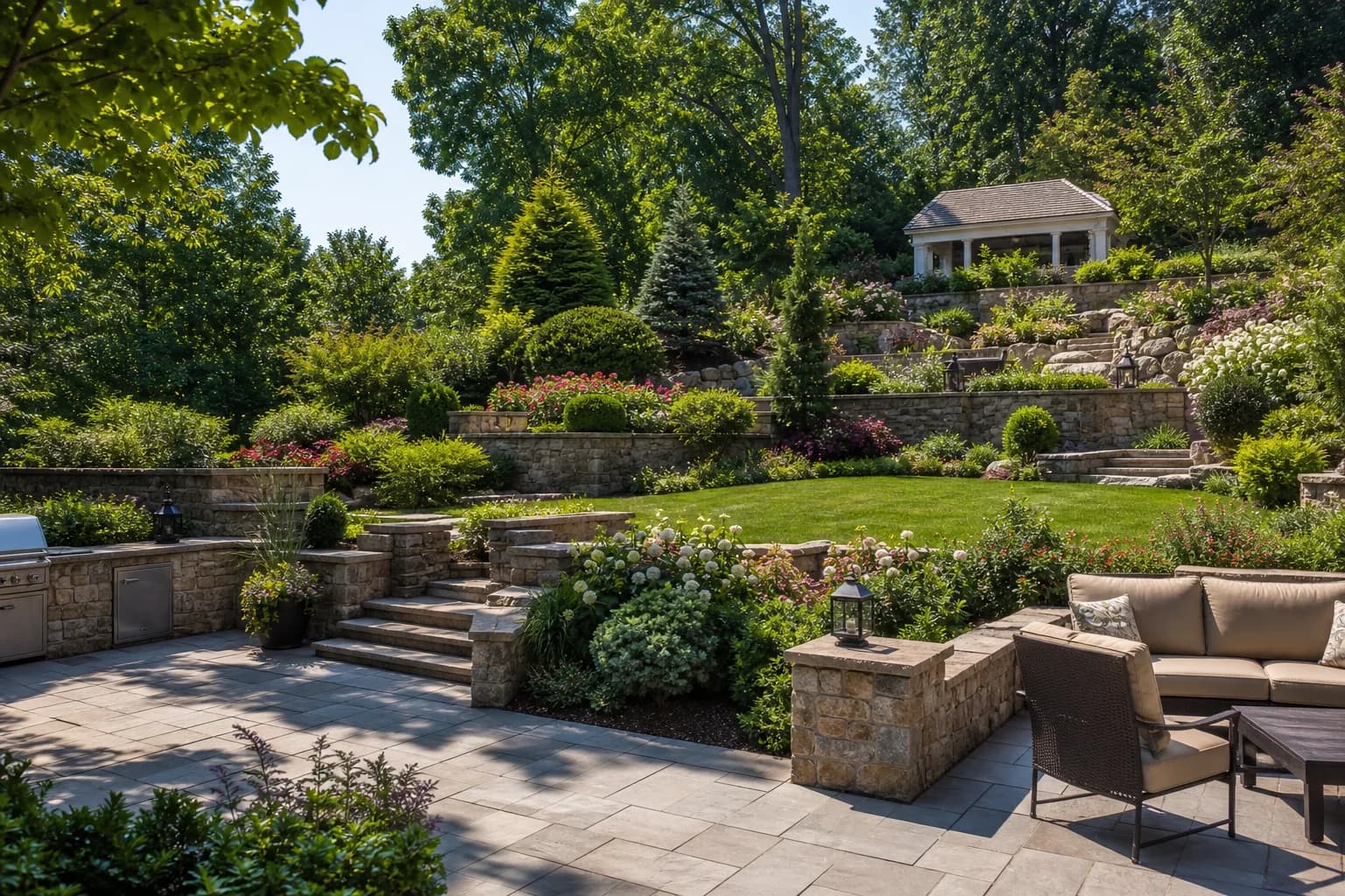 Large landscaped garden with multi-level terraces, natural stone walls and a wide paved patio
